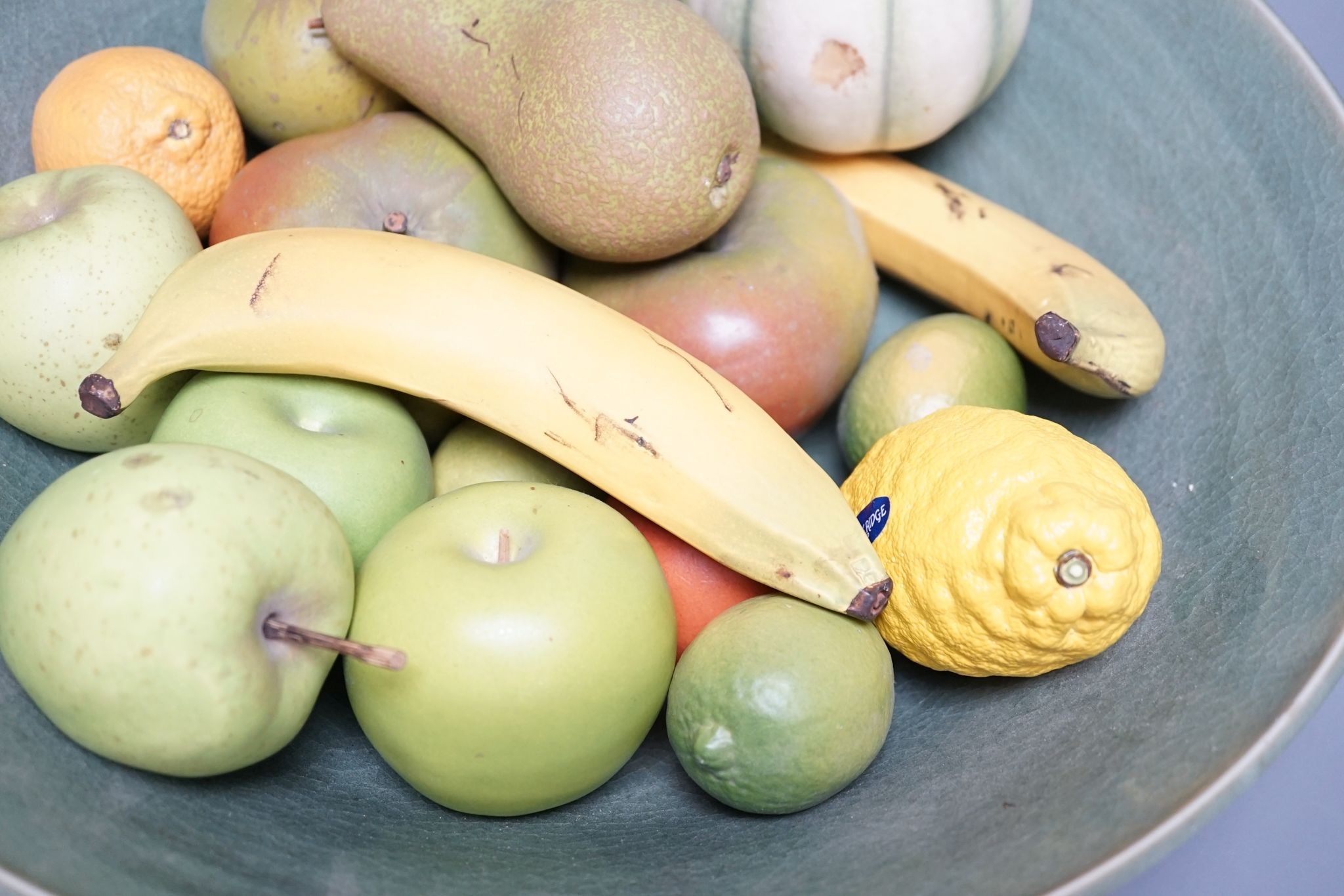 A collection of vintage Penkridge ceramic fruit including a pomegranate, melon, two bananas, limes, lemon, pear etc (18 items) in a green ceramic bowl, 42cm diameter